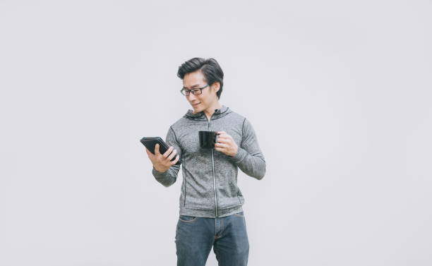 istock asian chinese mid adult handsome man drinking coffee using digital tablet videocall with hooded shirt on white background 1332871977