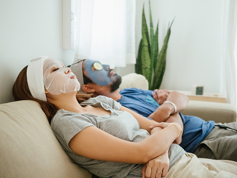 asian woman applying with clay carbo detox black mask to her face in bedroom at home.