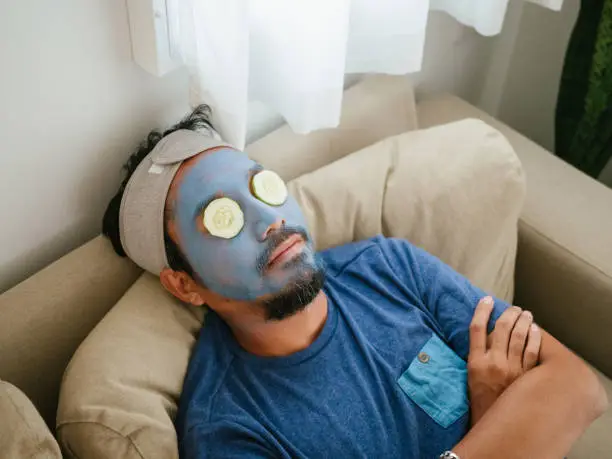 Asian man in bathroom with facial mask, Home spa and skin care concept.