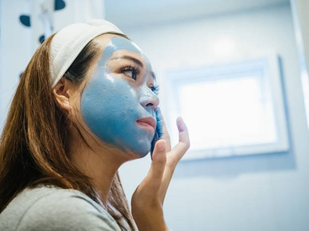 Woman doing face covered in moisturizing mask. Woman applying facial mask during coronavirus quarantine at home. people covered in mud stock pictures, royalty-free photos & images