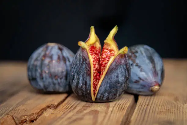 Fresh cut purple figs on a wooden background from old boards. Raw exotic figs. Low key