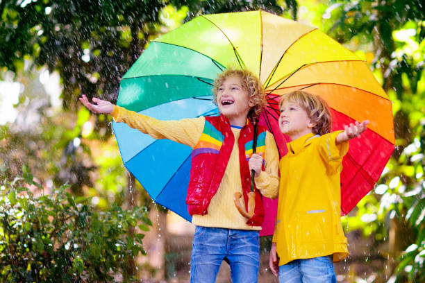 istock Child playing in autumn rain. Kid with umbrella. 1332880013