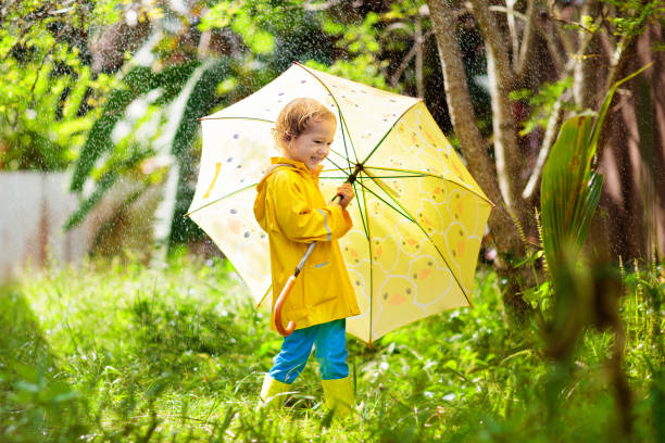 istock Child playing in the rain. Kid with umbrella. 1332880257