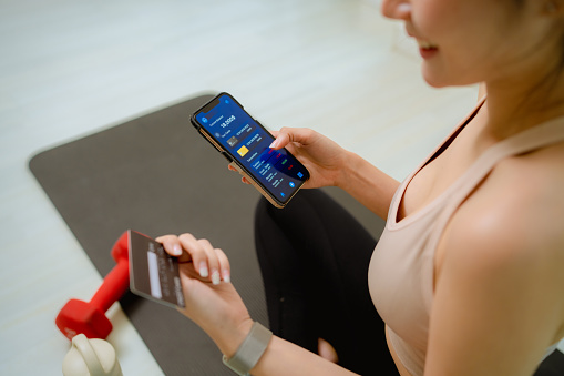 sports asian woman using smartphone delivery service and ordering healthy food online with smartphone after exercising at home