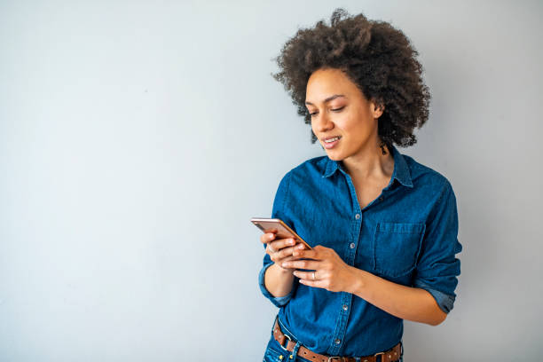 istock Smiling mature woman using smartphone isolated on gray wall with copy space. 1332885936