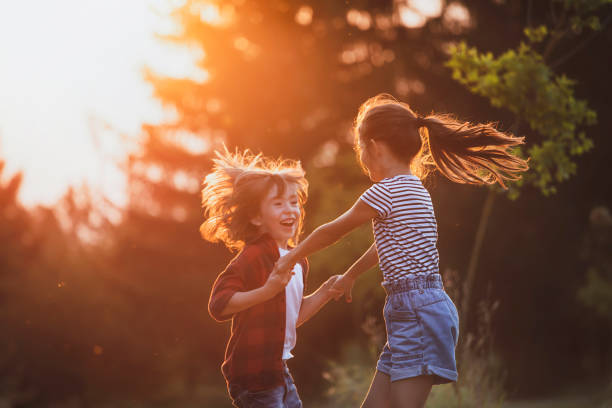 Two little friends playing outside. Enjoying the good weather. Happy in nature. Time together. Spring, summer time. Sunset