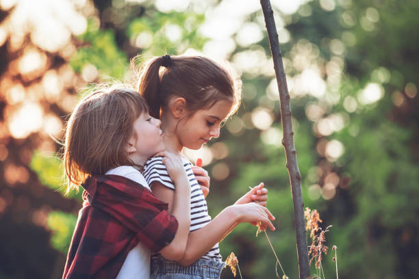 Two little friends playing outside. Enjoying the good weather. Happy in nature. Time together. Spring, summer time. Embracing. Love.