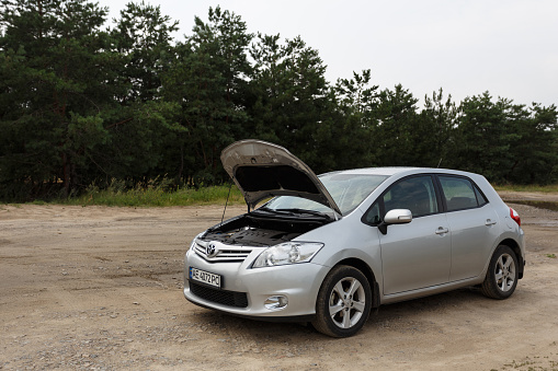Dnipro, Ukraine - July 30, 2021: Toyota Auris 2012 silver color with open hood. Summer rain