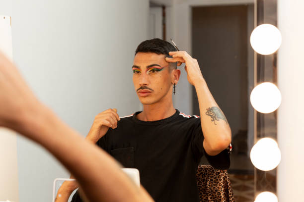 istock gay man with makeup looking in the mirror 1332900418