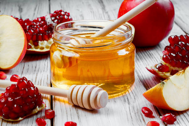 glas mit honig, äpfeln und granatäpfeln auf weißem holzhintergrund. frohes rosch haschana. traditionelle symbole der jüdischen neujahrsfeier. - shanah tova stock-fotos und bilder