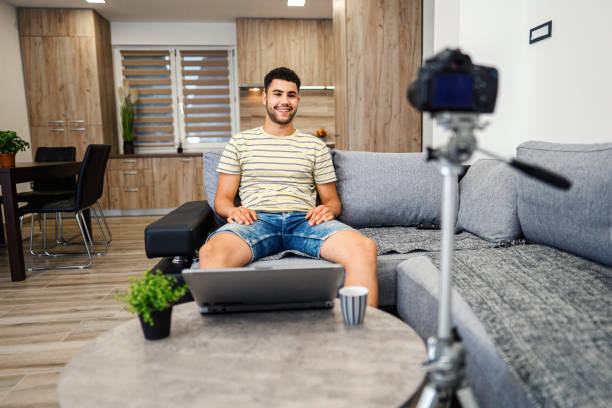 istock Young man making a video blog. Male vlogger recording content on digital camera. 1332915175