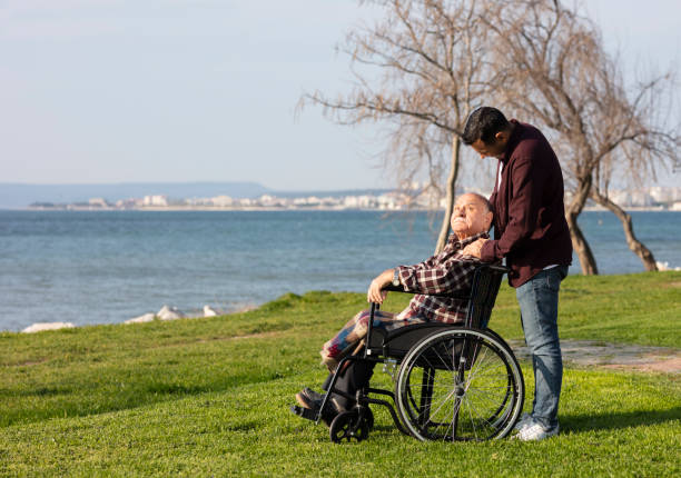 istock Elderly man in wheelchair with young man 1332922929