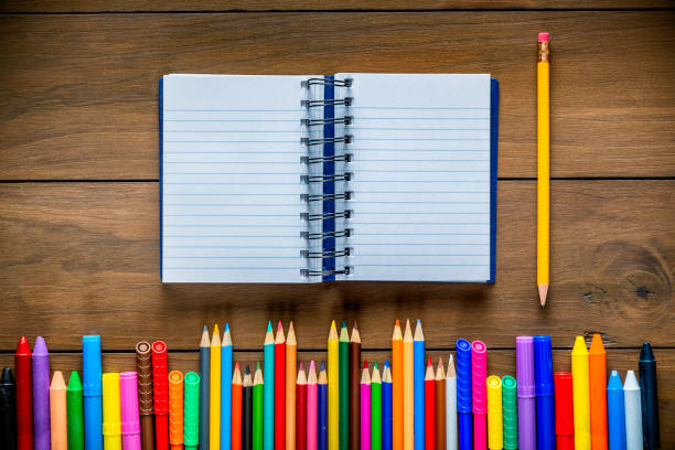 istock Overhead shot of wood table with assorted multi colored pencils and markers and a notebook with pencil 1332927621