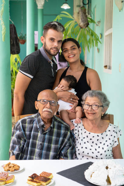 Family photo, infant, their parents and their great-grandparents Elderly couple sitting. A man and a woman with a child in their arms standing behind the elderly cuban ethnicity photos stock pictures, royalty-free photos & images