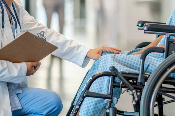 Girl in a wheelchair gets treatment A teen girl with a disability sits in a wheelchair and is helped by a doctor who approaches her in an empathetic way. asian multiple sclerosis stock pictures, royalty-free photos & images