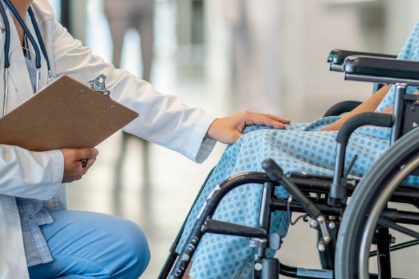 Girl in a wheelchair gets treatment A teen girl with a disability sits in a wheelchair and is helped by a doctor who approaches her in an empathetic way. sclerosis stock pictures, royalty-free photos & images