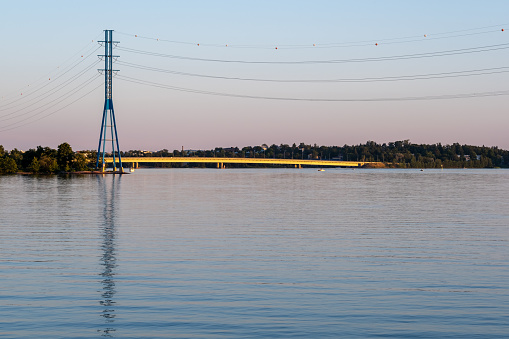 Helsinki / Finland - JUNE 29, 2021: A modern high voltage electricity pylon standing on the shore during sunset.