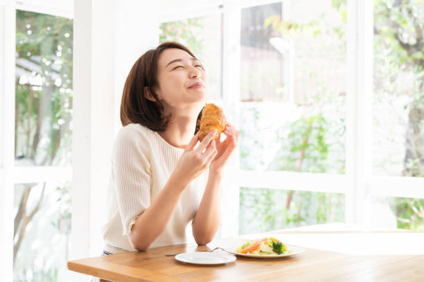 attractive asian woman who eats - window home interior women people imagens e fotografias de stock