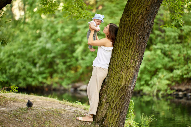 istock Woman holds child in hands while walking in park. 1332944382