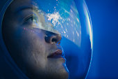 istock Asian chinese mid adult female astronaut looking at earth through window from spaceship at outer space 1332953647