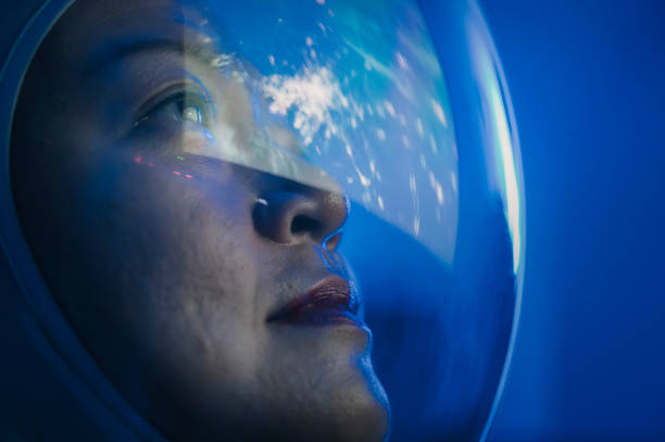 Asian chinese mid adult female astronaut looking at earth through window from spaceship at outer space Asian chinese mid adult female astronaut looking at earth through window from spaceship at outer space explorer stock pictures, royalty-free photos & images