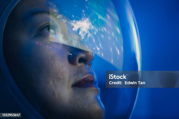 Asian Chinese Mid Adult Female Astronaut Looking At Earth Through Window From Spaceship At Outer Space Stock Photo - Download Image Now