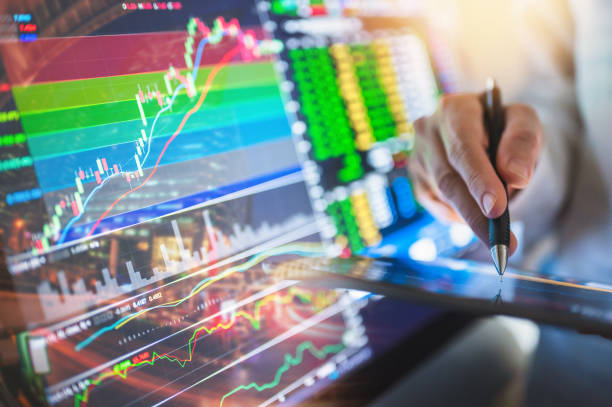 aking up very early to do some premarket trading, enjoying the freedom, day trading gives them or ending their day early after a good day of trading. primer plano del joven comerciante de nueva generación que trabaja con gráficos e informes financieros en la pantalla de la computadora y sostiene bitcoin en una mano mientras trabaja en su oficina moderna. cripto-moneda. moneda virtual. concepto de inve