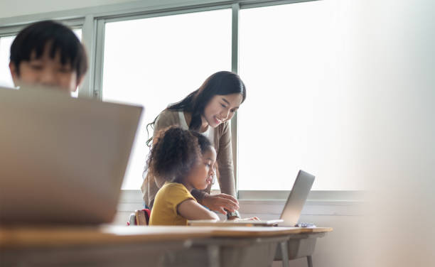 istock Diverse group of students and Asian female teacher learning on laptop 1332960556