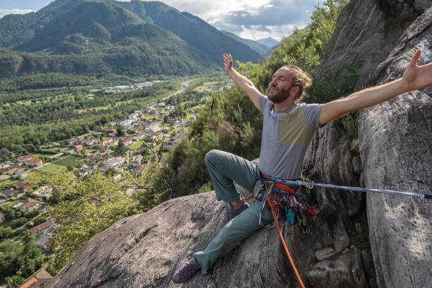 male mountain climber arms outstretched on mountain top - conquering adversity wilderness area aspirations achievement imagens e fotografias de stock