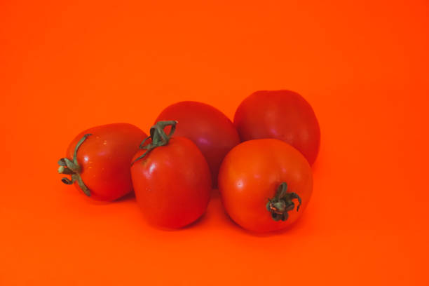 istock Fresh tomatoes in red on orange background 1332975946