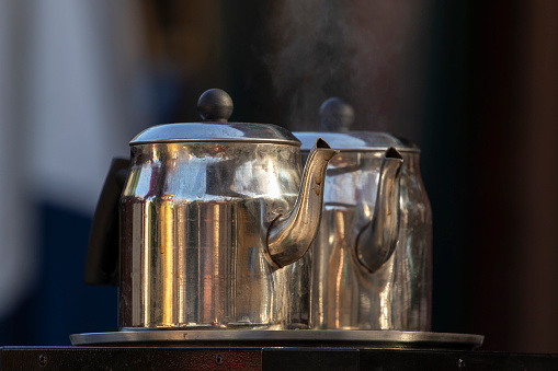 Metal teapots with hot drinks at street food vendors.