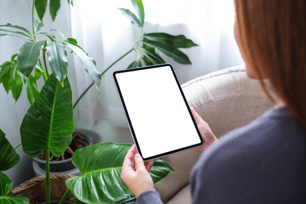 istock a woman holding digital tablet with blank white desktop screen at home 1332978113