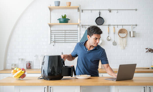 Portrait of asian Indian chef man cooking toast fried by Air Fryer machine in kitchen home. New normal work at home lifestyle. Technology eco friendly home smart device, asian single guy concept retrato del chef indio asiático que cocina tostadas fritas por la máquina de air fryer en la cocina de la casa. nuevo estilo de vida normal de trabajo en casa. tecnología ecológica para el hogar dispositivo inteligente, concepto asiático de un solo ho