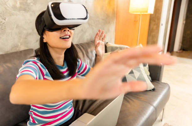 istock Young asian woman is using virtual reality headset. Neon light studio portrait. Concept of virtual reality, simulation, gaming and future technology.Asian woman play game in bedroom. 1332985339