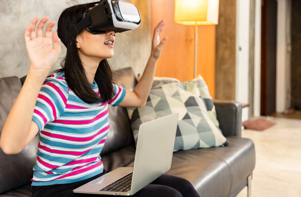 istock Young asian woman is using virtual reality headset. Neon light studio portrait. Concept of virtual reality, simulation, gaming and future technology.Asian woman play game in bedroom. 1332985346