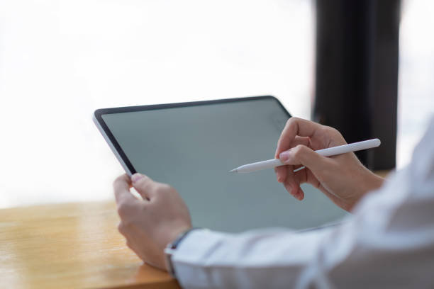 istock Woman hand with pen and a tablet blank white screen. 1332985405