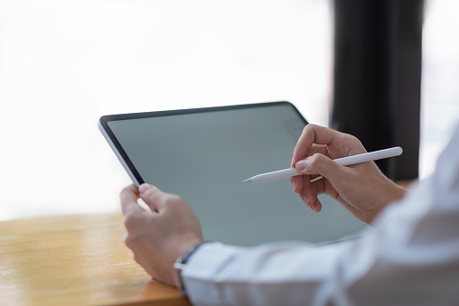 Woman hand with pen and a tablet blank white screen.