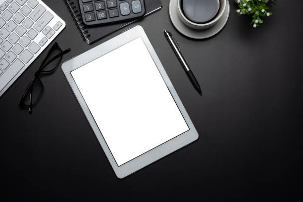 istock Top view of the workspace tablet blank white screen the work equipment is placed on the black wooden table at the office. Mockup. 1332985452