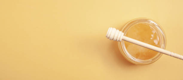 istock Honey jar with dipper on yellow background. 1332986034