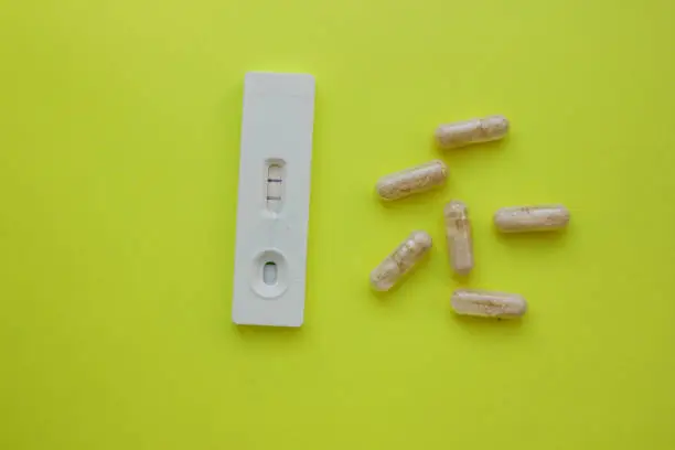 positive pregnancy test and pills on yellow background. Vitamins. Motherhood, children, pregnancy, the concept of birth control. Health problems and problems with conception. abortion. contraception.