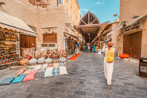 23 February 2021, Dubai, UAE: Tourist girl walking in the Old Bur Dubai souk market in Creek district. Sellers and merchants with textiles and souvenirs