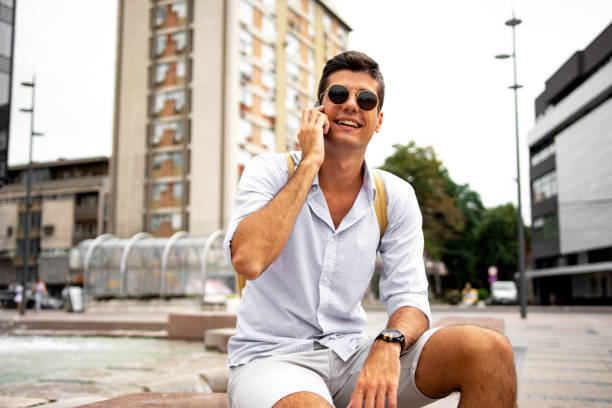 istock Handsome young man talking on a cellphone on the city street 1332995259