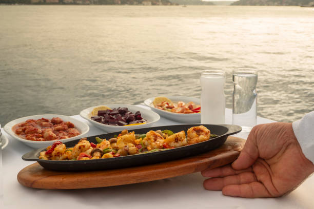 Waiter hand putting food on the table by the sea. Turkish food appetizers