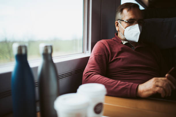 Attractive man travels on the train with an FFP2 mask because of the corona pandemic stock photo