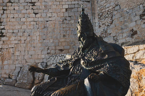 Peñiscola, Spain - July 28, 2021: Monument to Papa Luna, in Peniscola Castle, in Castellón (Valencia, Spain). This bronze statue sits at the ground of the castle of Papa Luna in Peñiscola. From 1415 to 1423 it was the home of the Avignon pope Benedict XIII (Pedro de Luna), whose name is commemorated in the Castell of Papa Luna, the name of the medieval castle.