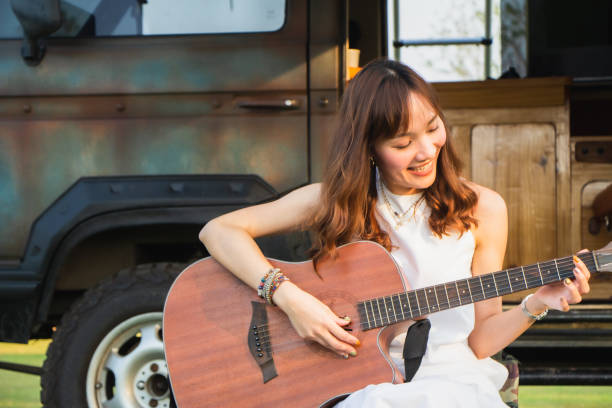 istock Young man and woman having fun and playing guitar and singing while summer vacation camping. 1333002921