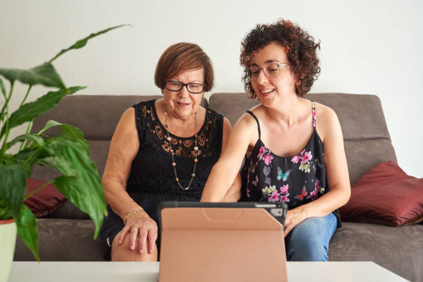 młoda kobieta uczy starszą matkę, jak korzystać z cyfrowego tabletu - ipad senior adult 70s adult zdjęcia i obrazy z banku zdjęć