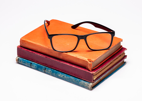 stack of old reading glasses and glass cases on a white background