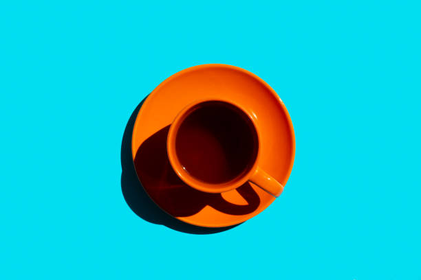 istock orange cup and saucer with black tea or coffee on the blue background. copy space. top view 1333010381