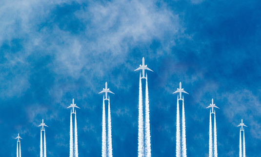 Airplanes flying in parallel in the blue sky forming an arrow shape.